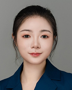 Counseling trainee smiling wearing blue collared shirt in front of grey backdrop.