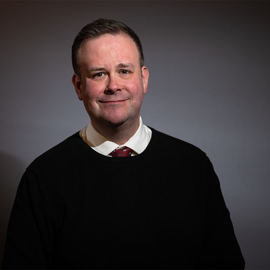 A man in a black shirt smiles at the camera.