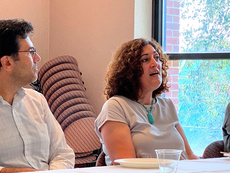 An instructor speaks while seated a table with colleagues.