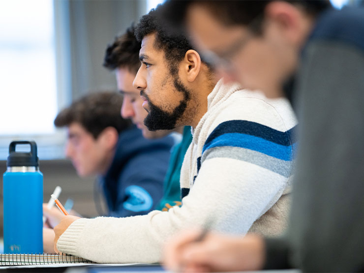 Students take notes and listen attentively in a classroom.