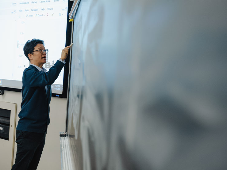 A college professor writes on a chalkboard.