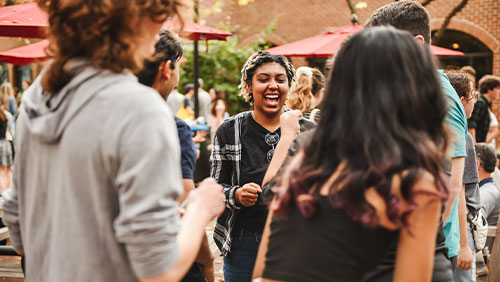 College students laugh and talk in a crowded plaza.