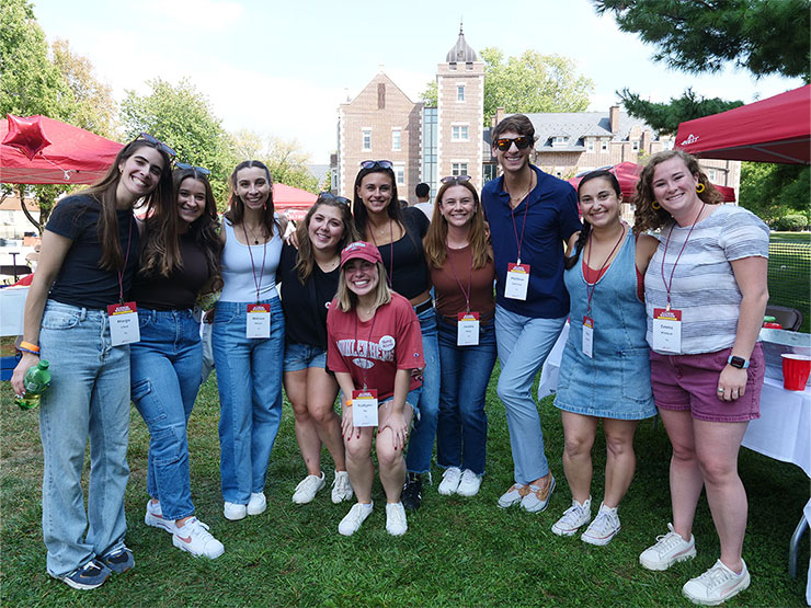 A smiling group of Muhlenberg alumni pose together outdoors on campus.