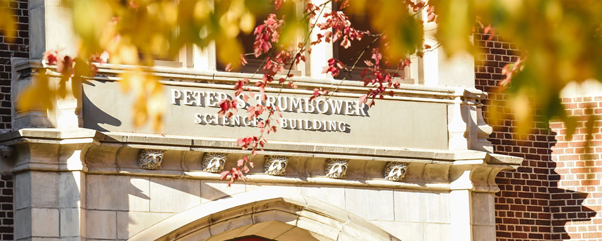 The entrance to the Peter S. Trumbower Science Building is flanked by colorful fall foliage.