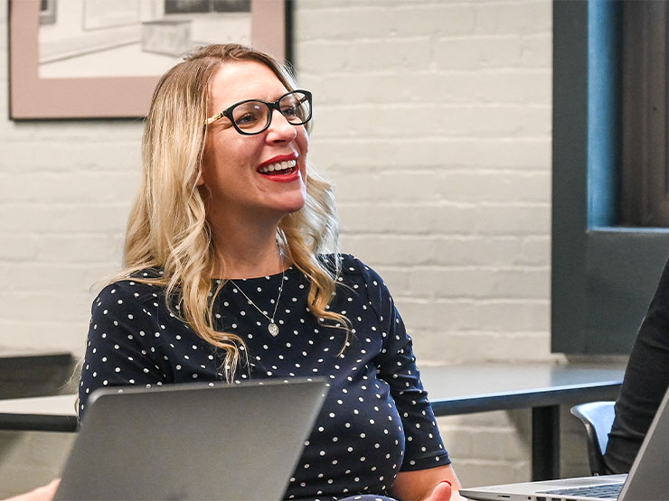An adult students smiles while seated in a classroom.