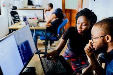 Two students sitting next to each other looking at a computer screen