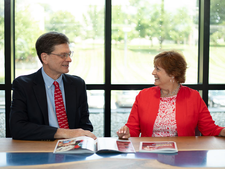 Two professionals involved in Muhlenberg graduate studies chat at a table.