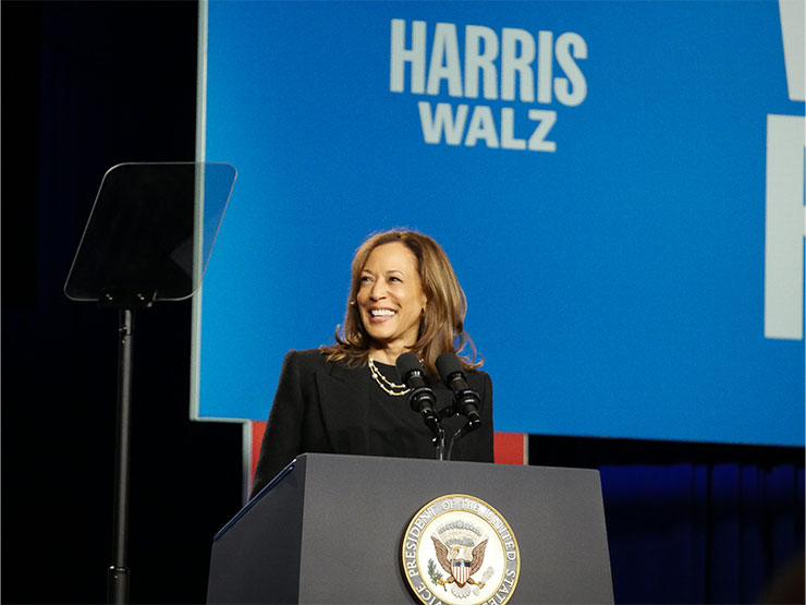 Vice President Kamala Harris smiles behind a podium in a gymnasium at Muhlenberg College.