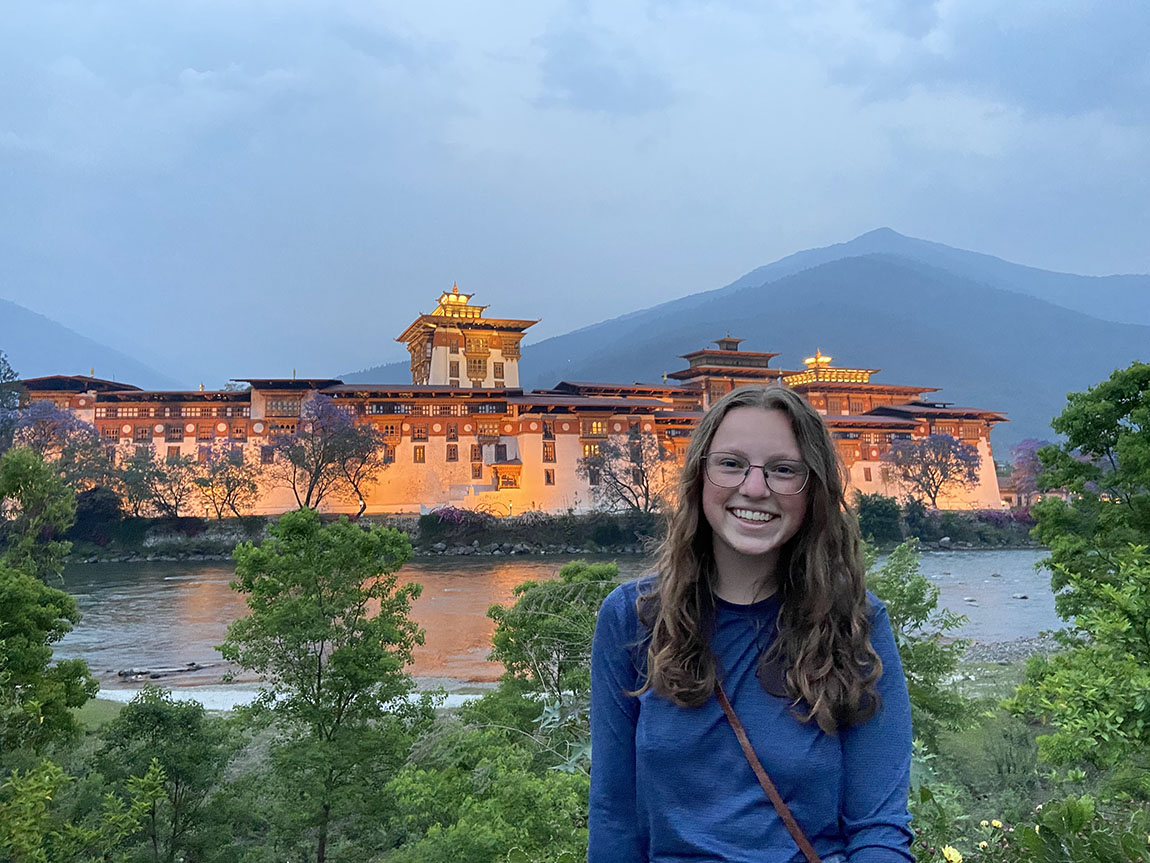 A smiling college student in front of a building in Bhutan