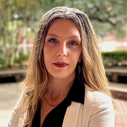 A college professor with long light brown hair photographed outside