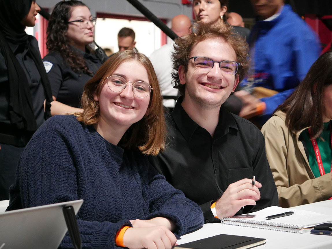 Two college students pose for a photo in the press area of a political rally