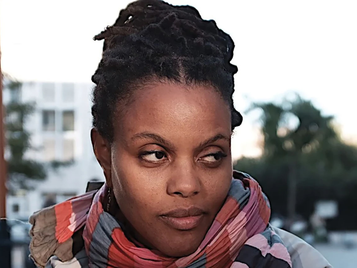 A woman wearing a scarf outside looks to the side