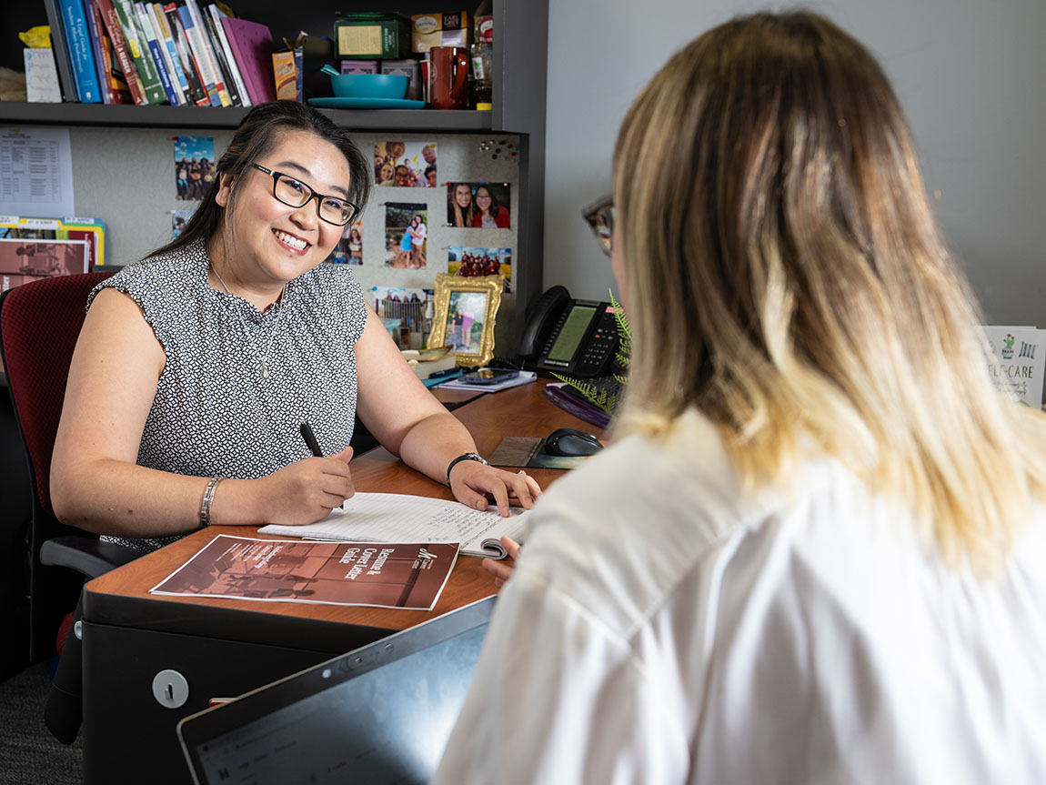 A college career coach smiles at a college student sitting across from her