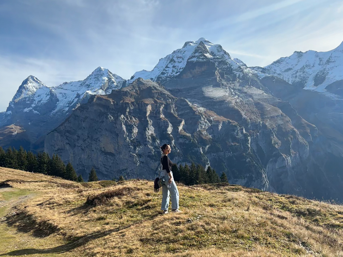 A college student stands in front of snow-capped mountains in Switzerland