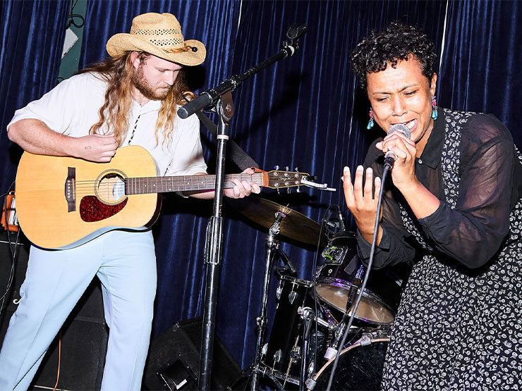 A guitarist and singer perform on stage.